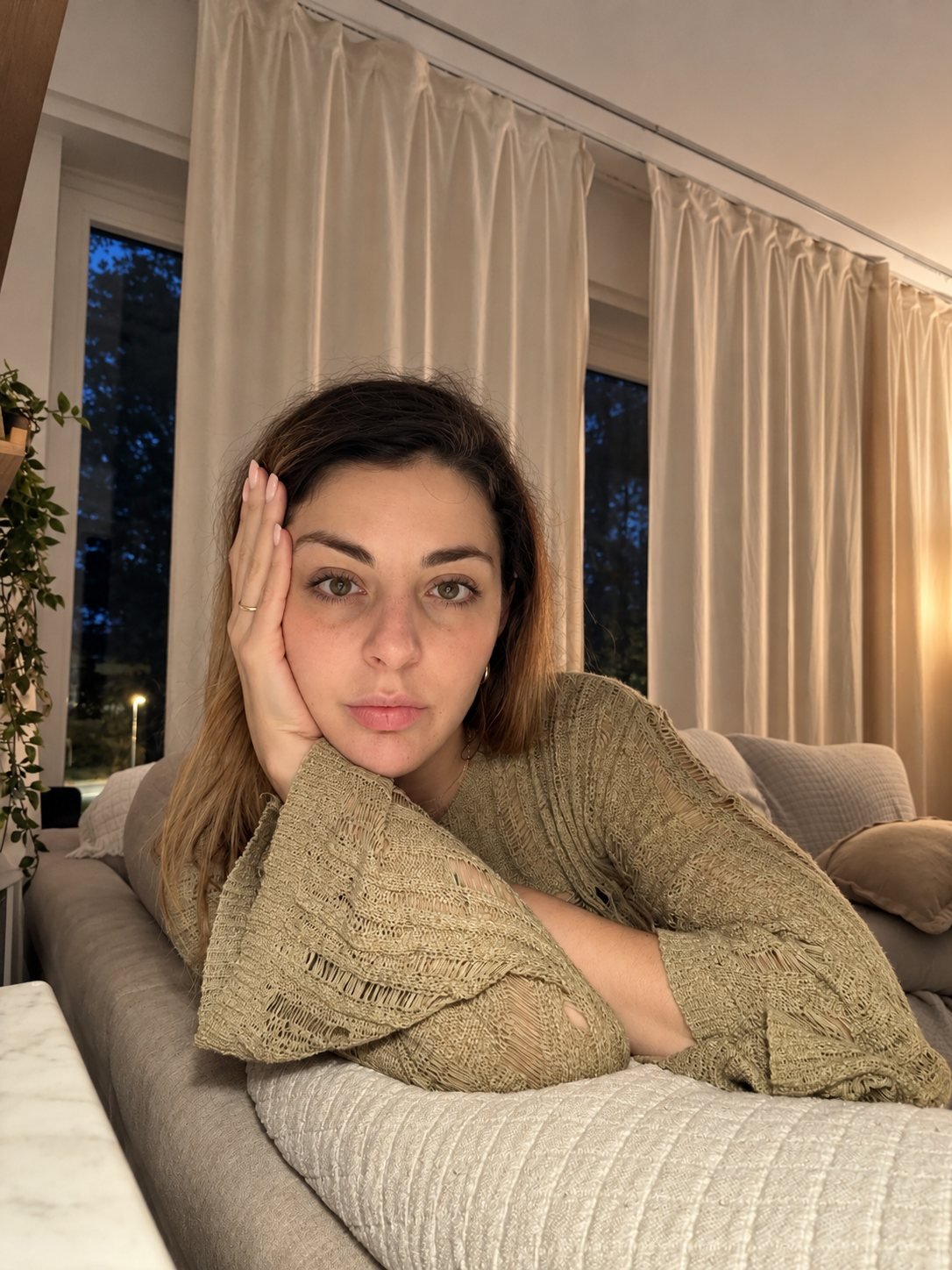 Author Alex Martino resting her head on her hand in a softly lit living room