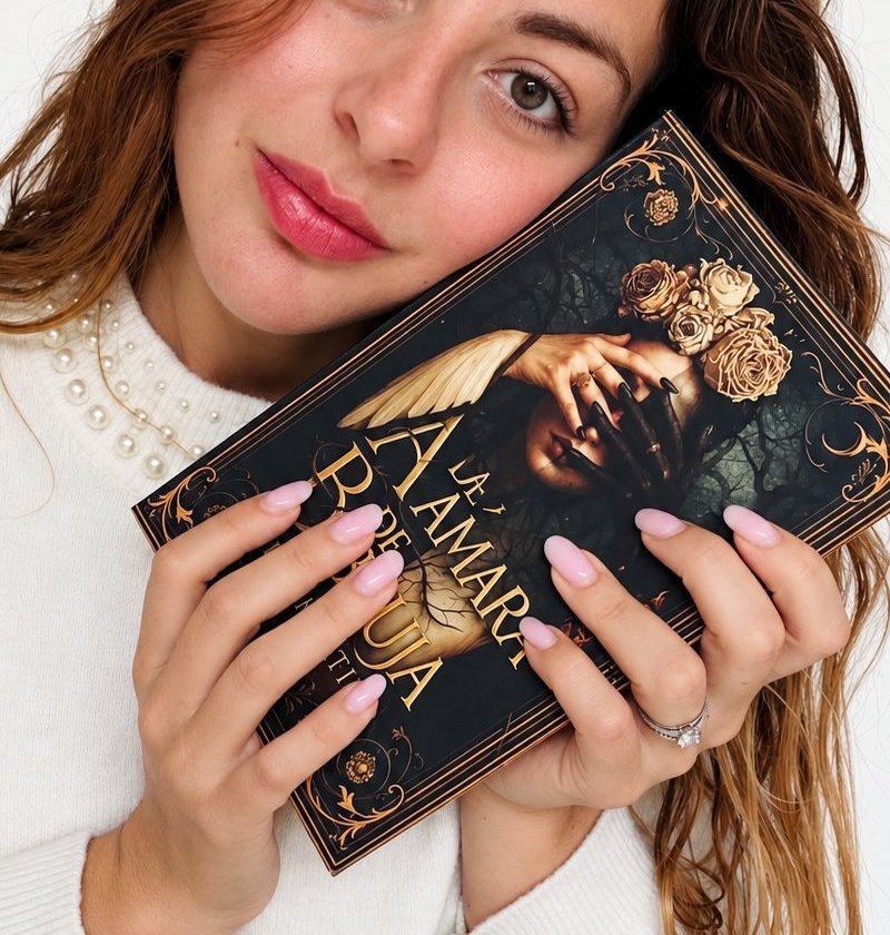 Cover of Á de Ámara B de Bruja: a woman crowned with roses and a feathered wing, framed in gold filigree